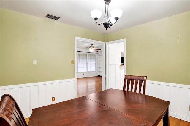 unfurnished dining area with wood-type flooring and ceiling fan with notable chandelier