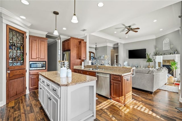 kitchen featuring appliances with stainless steel finishes, white cabinetry, sink, hanging light fixtures, and a center island