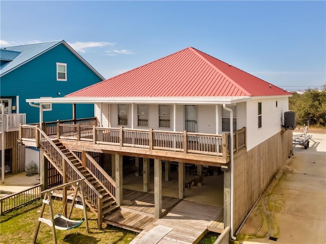 rear view of house with metal roof, fence, a deck, and cooling unit