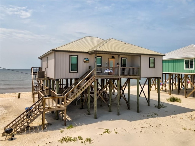 rear view of house with a water view and a beach view