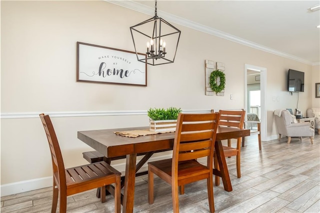 dining room with a notable chandelier, ornamental molding, and light wood-type flooring