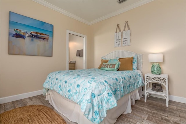 bedroom with hardwood / wood-style flooring, crown molding, and ensuite bath