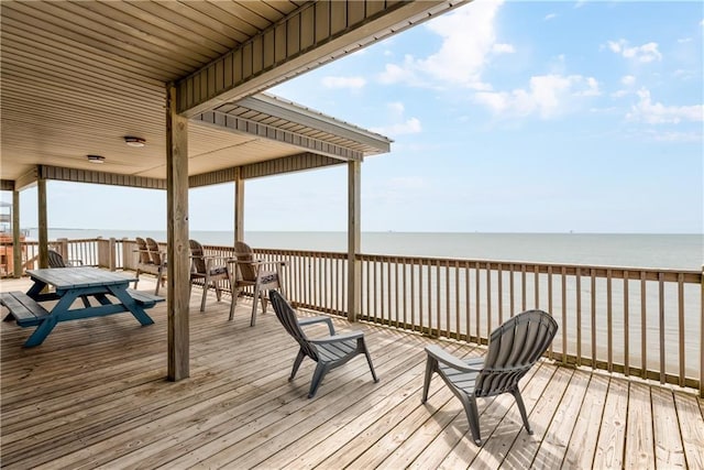 wooden terrace featuring a water view and a view of the beach