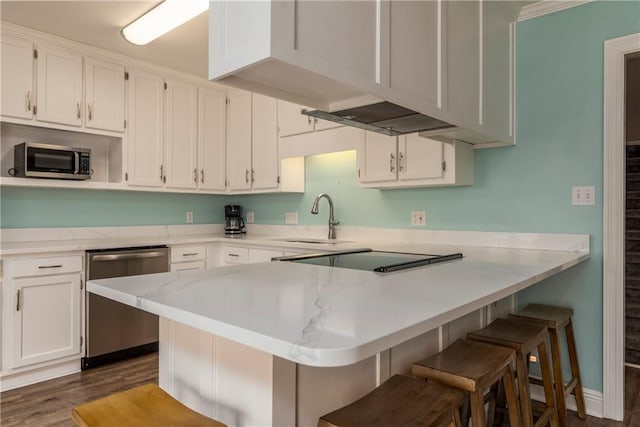 528 Lemoyne Dr Unit 2C, Dauphin Island, AL 36528 - kitchen with stainless steel appliances, white cabinets, a peninsula, a breakfast bar area, and dark wood finished floors