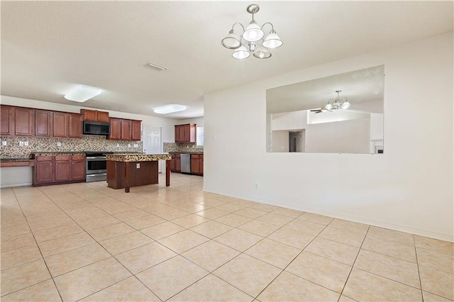 kitchen with backsplash, stainless steel appliances, a notable chandelier, and light tile patterned flooring