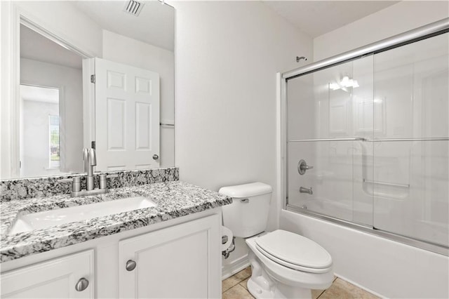 full bathroom featuring shower / bath combination with glass door, tile patterned flooring, vanity, and toilet