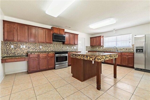 kitchen with a center island, backsplash, a textured ceiling, light tile patterned flooring, and appliances with stainless steel finishes