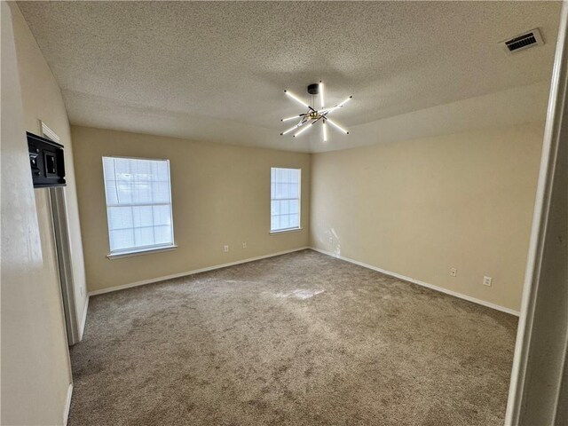 empty room with carpet floors and a textured ceiling