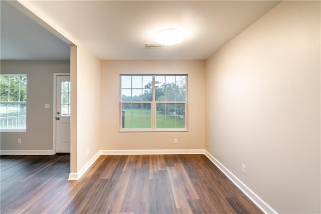 empty room with visible vents, baseboards, and dark wood-style flooring