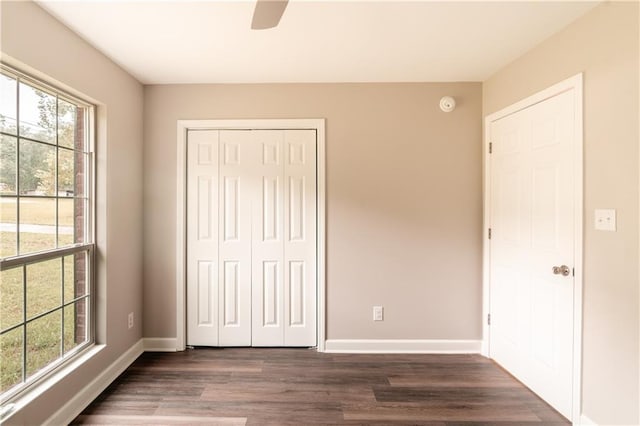 unfurnished bedroom with multiple windows, baseboards, and a closet