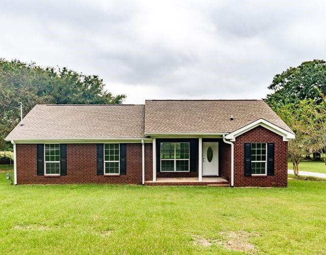 single story home featuring brick siding, roof with shingles, and a front yard