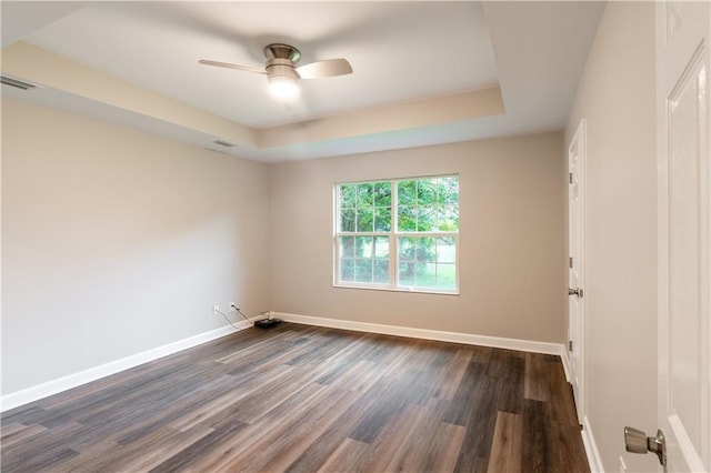 empty room featuring visible vents, a raised ceiling, and baseboards