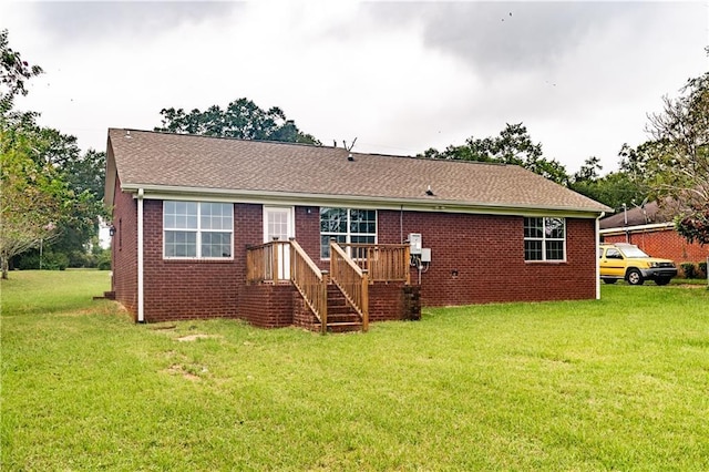 back of house featuring brick siding, a lawn, and roof with shingles