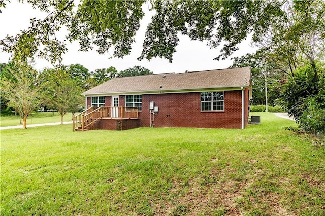 back of property with central air condition unit, a lawn, and brick siding