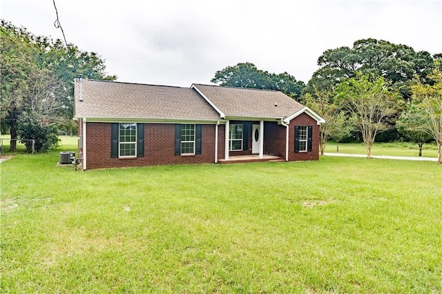 single story home with brick siding, central air condition unit, and a front lawn