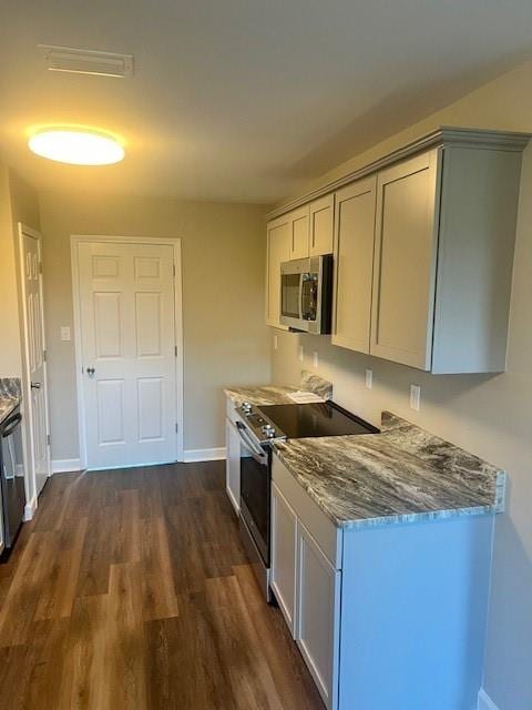 kitchen with dark wood-type flooring, light stone counters, and stainless steel appliances