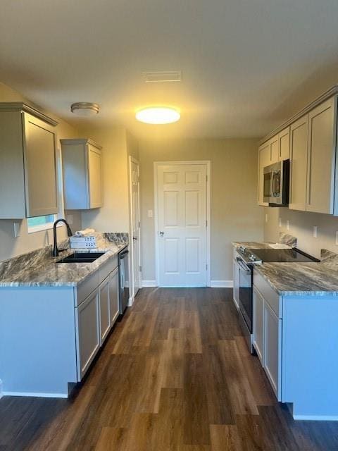 kitchen with light stone counters, stainless steel appliances, sink, and dark hardwood / wood-style floors