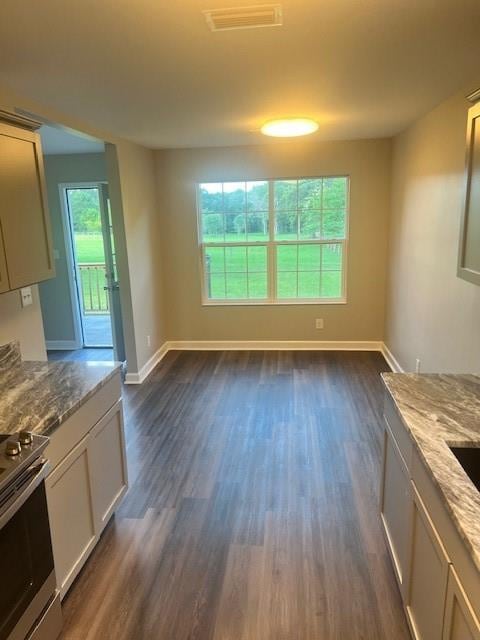 kitchen with stainless steel range oven, light stone countertops, and dark hardwood / wood-style floors