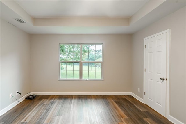 unfurnished room with dark wood finished floors, visible vents, a raised ceiling, and baseboards