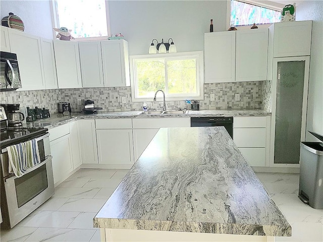 kitchen with marble finish floor, appliances with stainless steel finishes, white cabinets, a kitchen island, and a sink