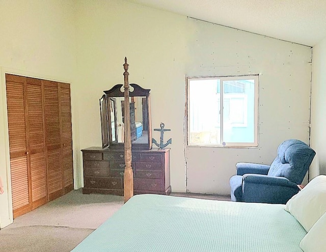 bedroom with vaulted ceiling, a closet, and light colored carpet