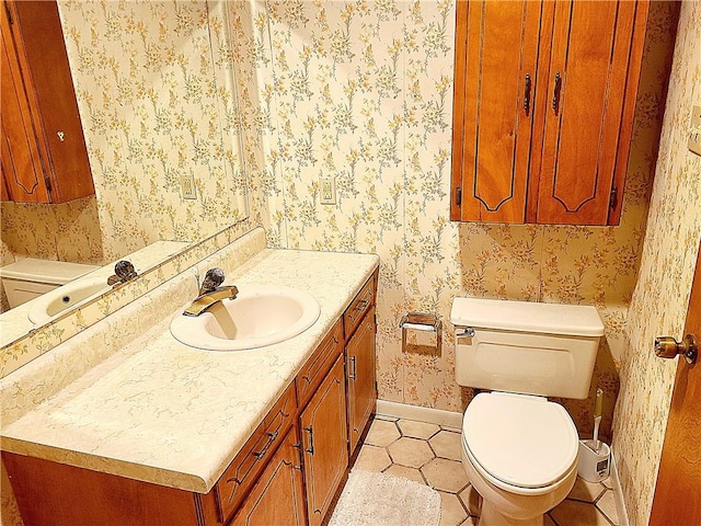 half bathroom featuring wallpapered walls, baseboards, toilet, tile patterned flooring, and vanity