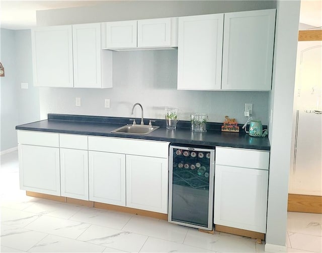 kitchen with wine cooler, a sink, white cabinets, marble finish floor, and dark countertops