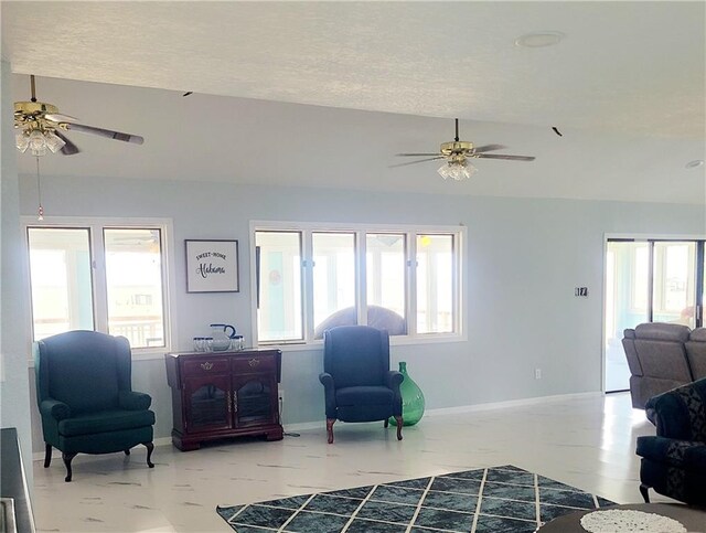 sitting room with ceiling fan, plenty of natural light, and vaulted ceiling