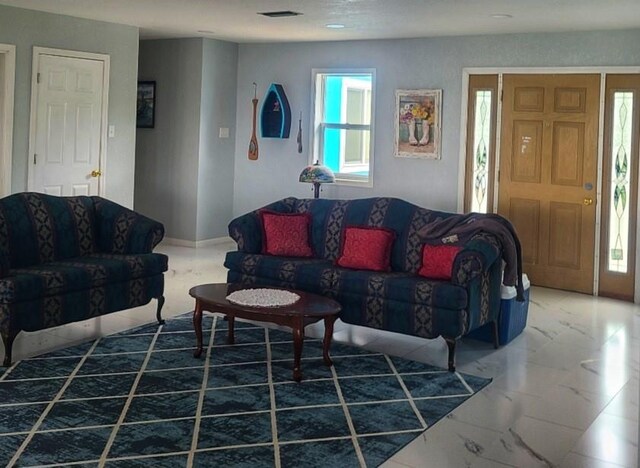 living area featuring a wealth of natural light, marble finish floor, and visible vents