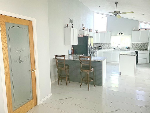 kitchen featuring marble finish floor, black appliances, a center island, and white cabinets