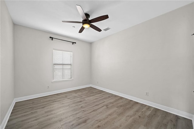 unfurnished room with a ceiling fan, visible vents, baseboards, and wood finished floors