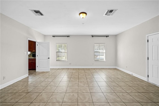 spare room featuring a healthy amount of sunlight, visible vents, and baseboards