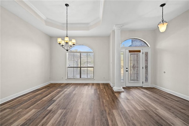 entryway featuring ornate columns, a chandelier, a raised ceiling, and wood finished floors