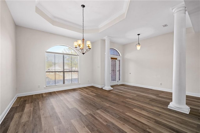 interior space featuring dark wood-type flooring, visible vents, baseboards, a tray ceiling, and decorative columns