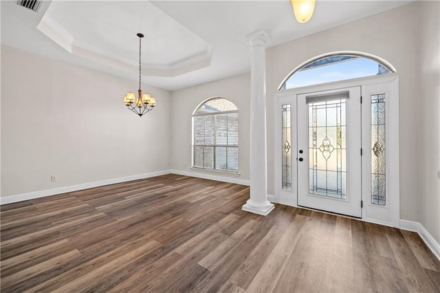 entryway featuring a chandelier, wood finished floors, baseboards, a tray ceiling, and decorative columns