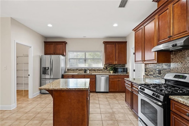 kitchen with light tile patterned floors, under cabinet range hood, a sink, visible vents, and appliances with stainless steel finishes