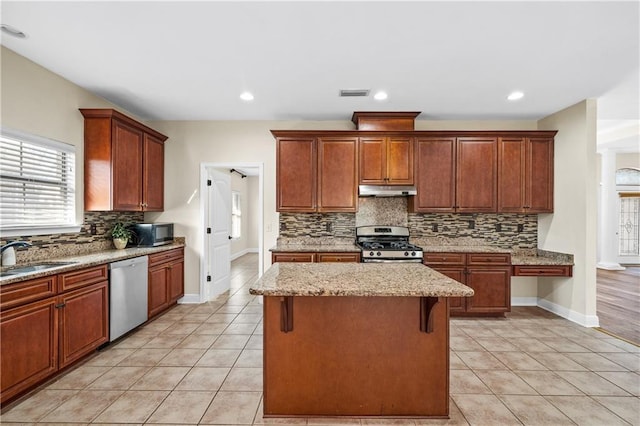 kitchen featuring stainless steel appliances, a kitchen island, light tile patterned flooring, and a sink