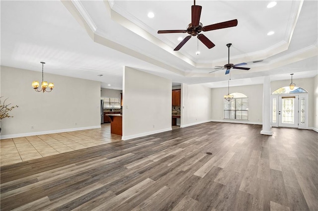 unfurnished living room featuring dark wood-style floors, baseboards, a tray ceiling, and ornamental molding