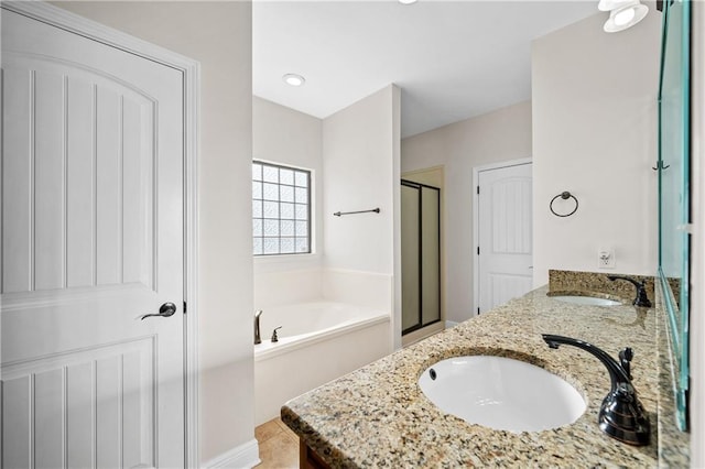 bathroom featuring double vanity, a garden tub, a sink, and a stall shower