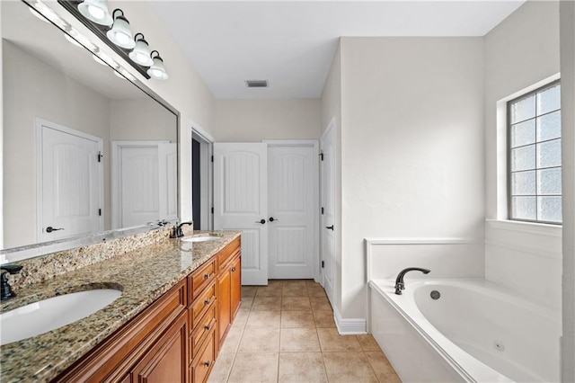 bathroom with a sink, double vanity, a tub with jets, and tile patterned flooring