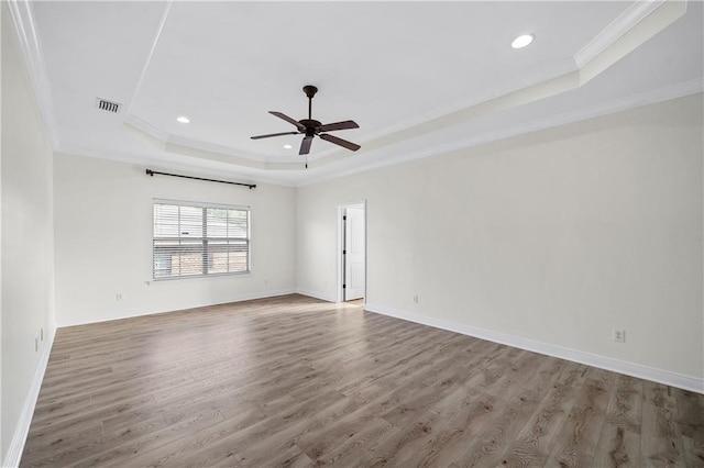 unfurnished room featuring a raised ceiling, visible vents, ornamental molding, ceiling fan, and wood finished floors