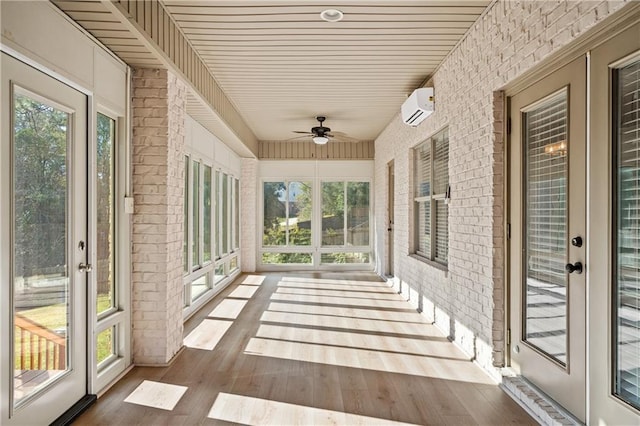 unfurnished sunroom featuring ceiling fan and a wall mounted air conditioner