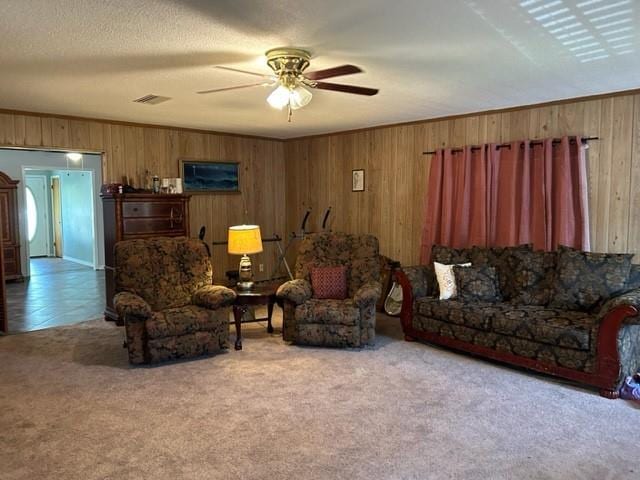 carpeted living room featuring ceiling fan, a textured ceiling, and wood walls