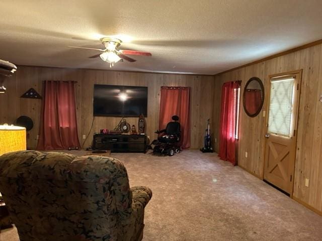 living room with crown molding, ceiling fan, light colored carpet, a textured ceiling, and wood walls