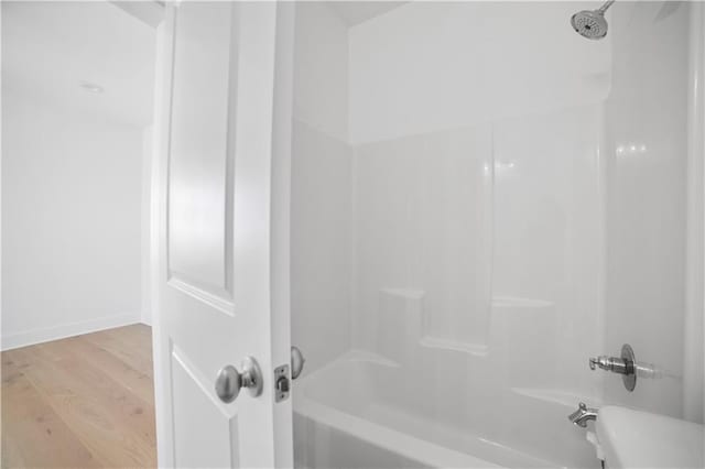 full bath with wood finished floors,  shower combination, and baseboards