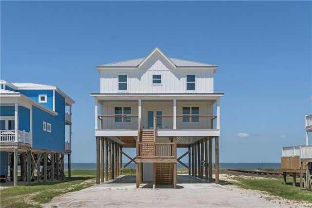 beach home featuring a carport, board and batten siding, dirt driveway, and a water view