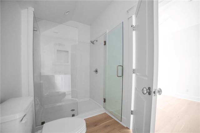 full bath featuring toilet, wood finished floors, and a shower stall