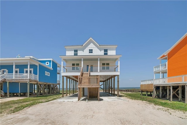 view of front facade featuring a carport, stairway, driveway, board and batten siding, and a porch