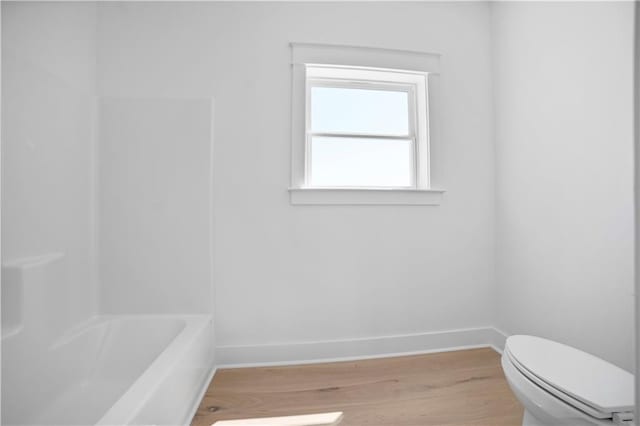 bathroom featuring wood finished floors, baseboards, and toilet
