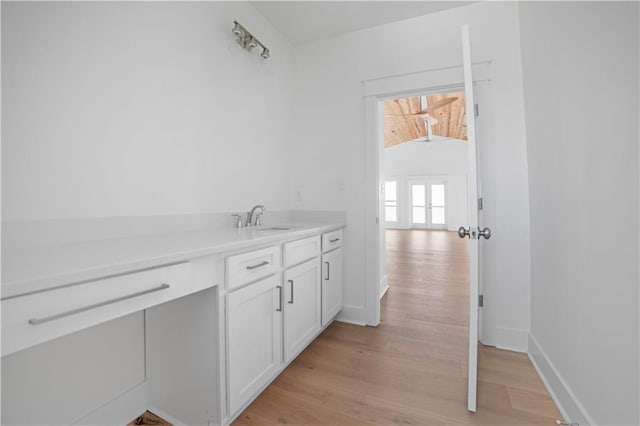bathroom featuring wood finished floors, a sink, and baseboards